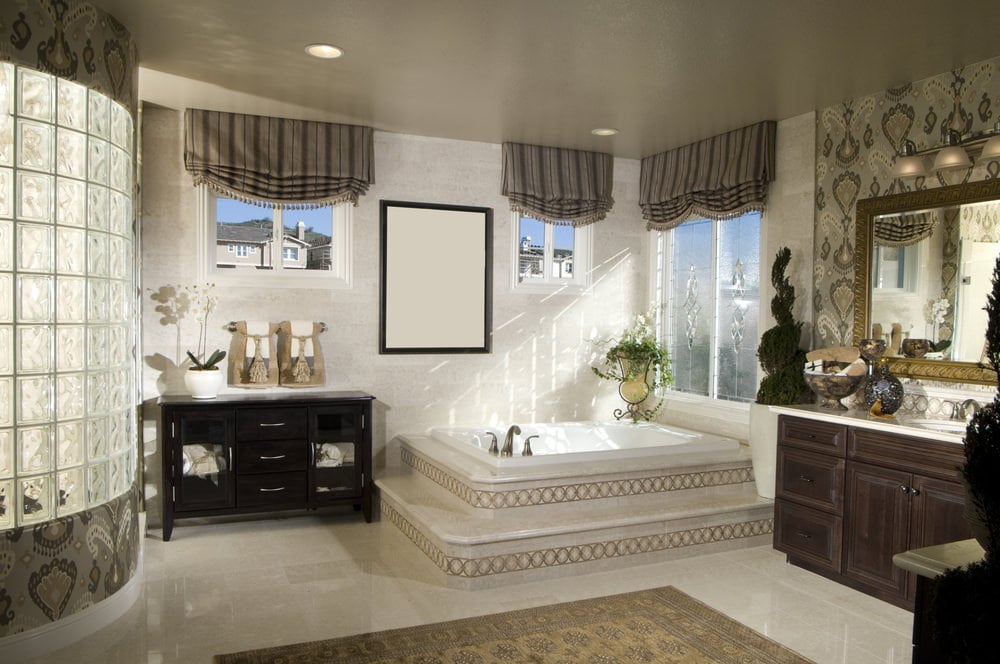 优雅的白色主浴室，带一个令人惊叹的淋浴房和一个优雅的浴缸。瓷砖地板上铺着漂亮的地毯。