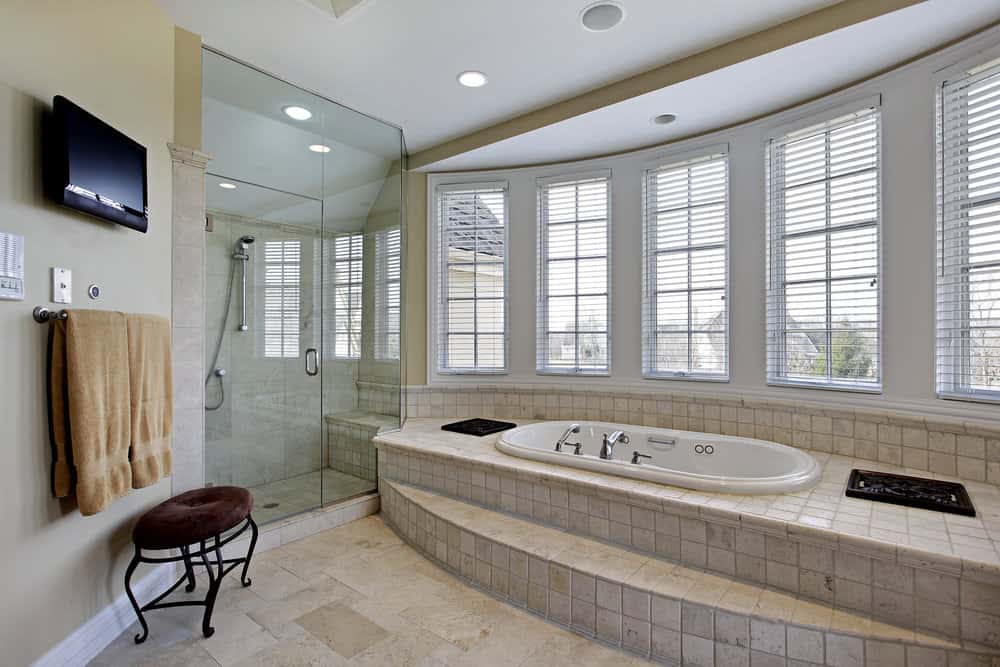 主浴室采用灰色墙壁和瓷砖地板。它拥有靠近窗户的瓷砖平台上的一个浴缸和一个步入式的角落淋浴间。
