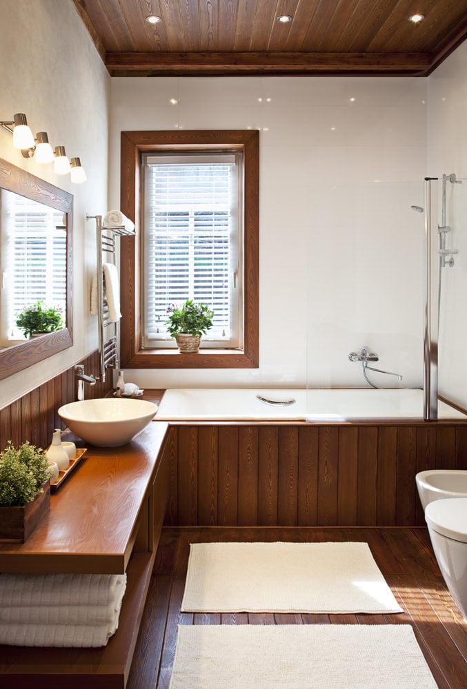 带有硬木地板的现代主浴室和带水槽的木质柜台，以及角落里的浴缸。