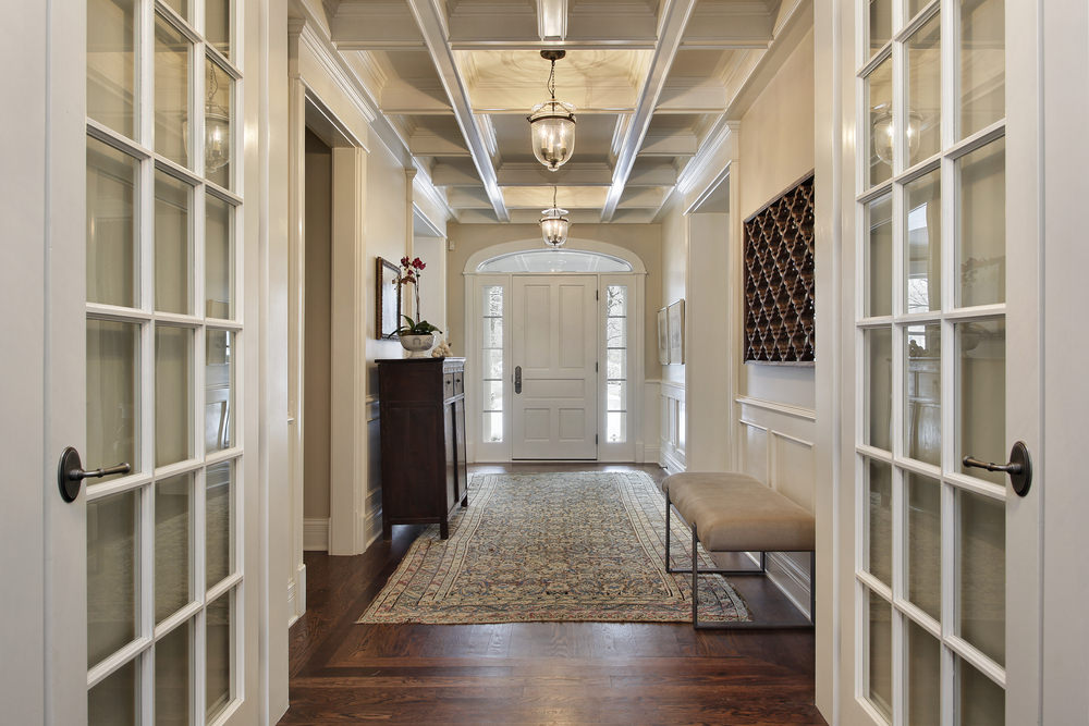 这个优雅的小门厅设有硬木地板，上面有一个优雅的地毯。格子天花板和吊灯看起来很华丽。