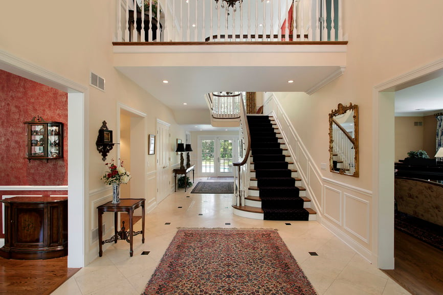 一个有瓷砖地板和白墙的高档住宅的入口。楼梯以黑色优雅的地毯为特色。