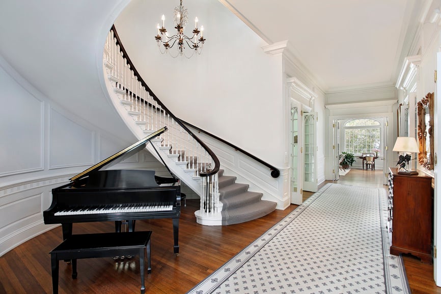 这所房子的入口有一个带有灰色地毯地板的弯曲楼梯。屋内的硬木地板上还有一架黑色钢琴。
