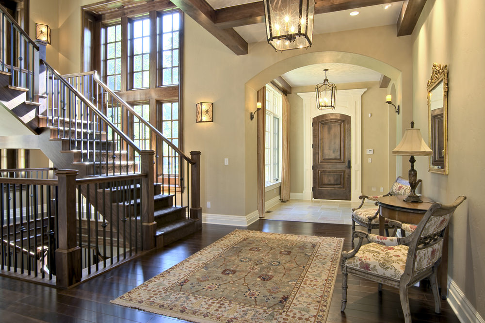 门厅设有螺旋楼梯，设有木质台阶和铁栏杆。地板上铺着漂亮的地毯，旁边还有一套漂亮的椅子。