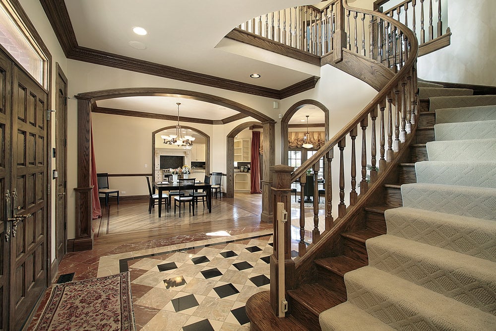 一个令人惊叹的住宅入口，有一个覆盖着地毯地板的大弯曲楼梯。