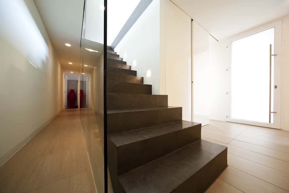 狭长的走廊，混凝土直楼梯固定玻璃栏杆，楼梯灯照明。