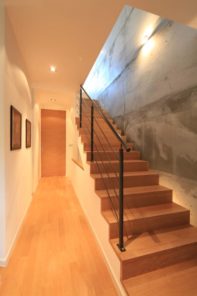 明亮的走廊拥有白色的墙壁和硬木地板，与配有黑色栏杆的楼梯相辅相成。