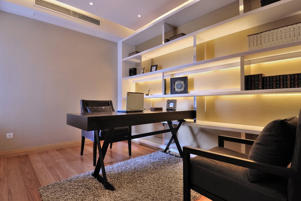 大型家庭办公室设有现代化的架子和一个时尚的家庭办公桌以及舒适的椅子设置在硬木地板上。
