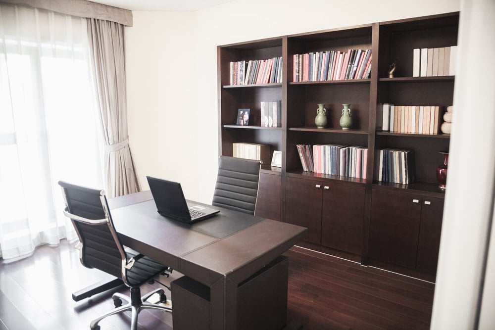 这个家庭办公室提供了相对的黑色椅子，深色的木桌与书架相映成趣。