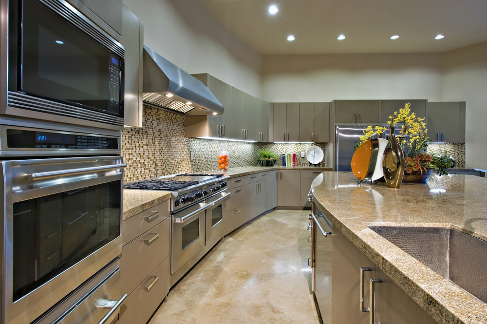 这间厨房设有一个大型中央岛台，与厨房柜台类似的花岗岩台面。它以优雅的瓷砖地板和灰色橱柜为特色。