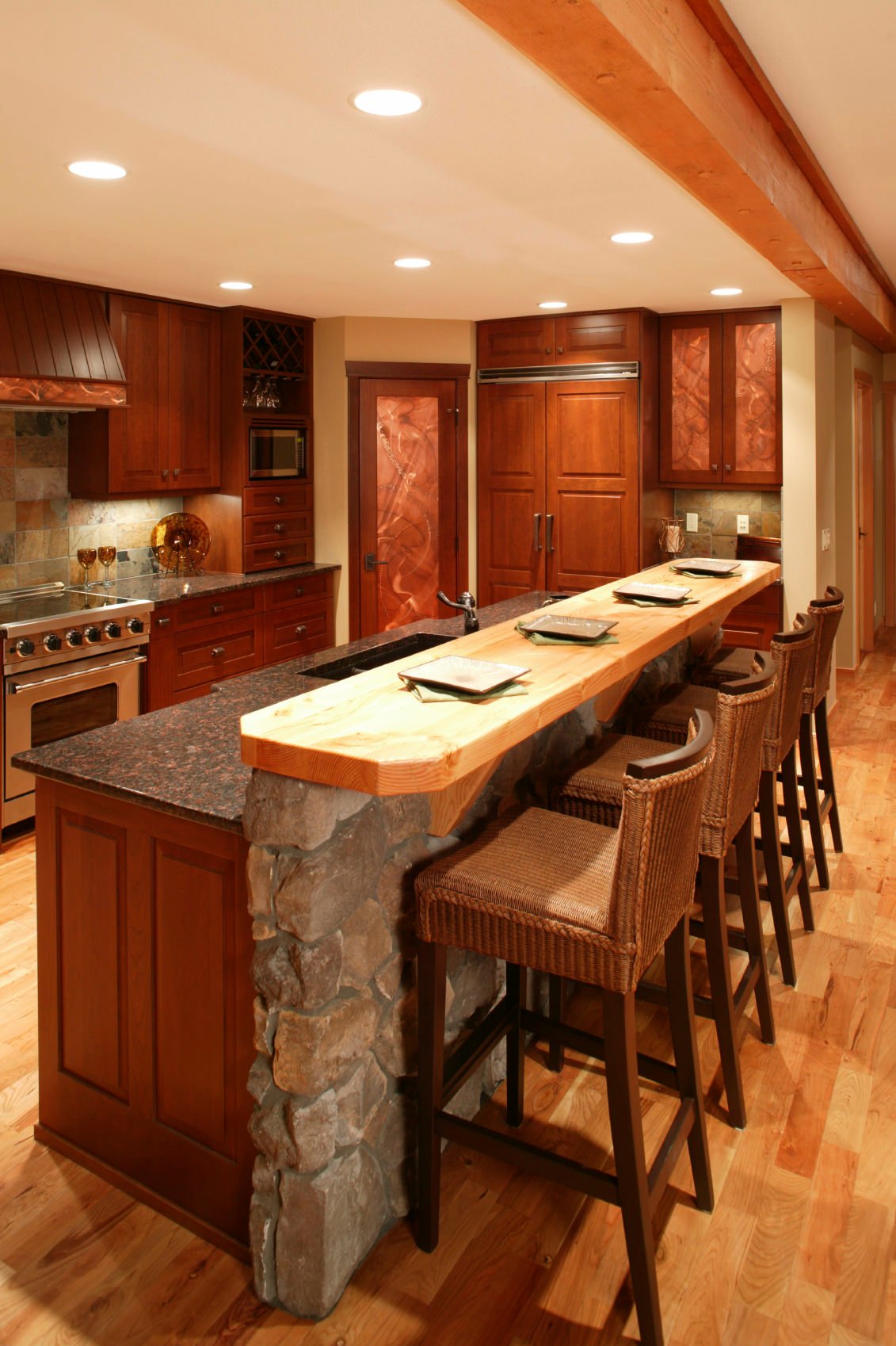 乡村风格的厨房配有红色调的木橱柜，两层酒吧风格的厨房，上层有木制表面的石头底座。