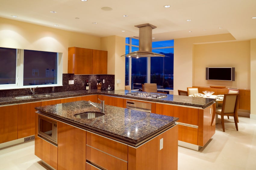 这间厨房的花岗岩台面与胡桃木橱柜搭配得很好。凹形灯为房间的风格增添了优雅的氛围。