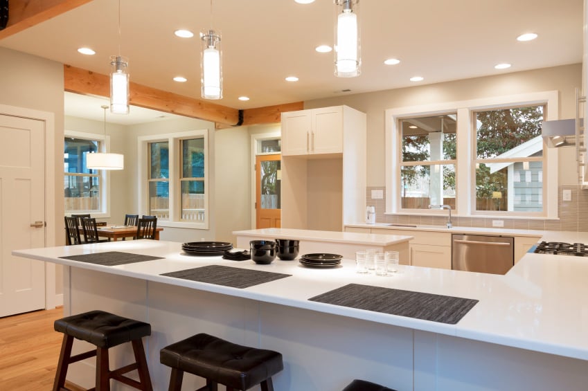 这个厨房的特色是光滑的白色柜台遍布整个厨房，由嵌入式和吊灯照明。