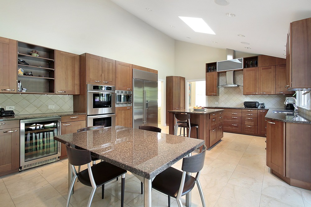 大型厨房设有棕色橱柜和带黑色花岗岩台面的厨房柜台。地板和棚顶看起来很有格调。