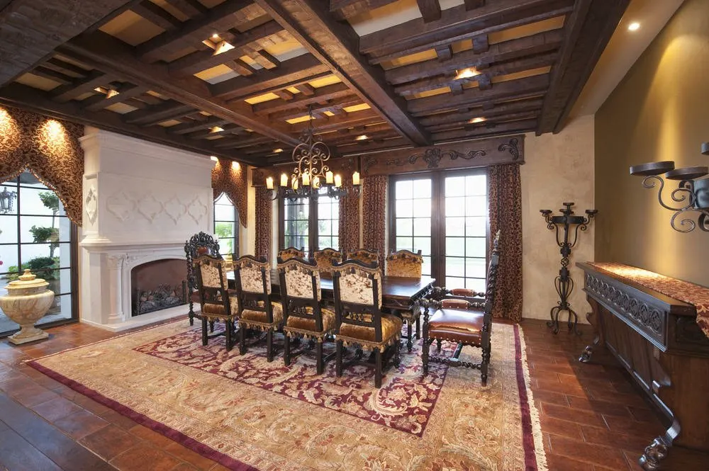经典餐厅terracotta地板和窗户全高度覆盖的织物和效价。它包括一个白色的壁炉和木制的桌子上摆放着一套用餐。