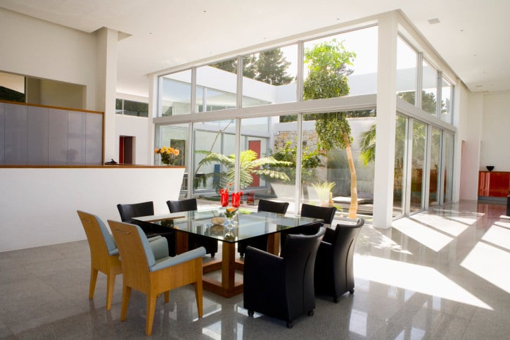 餐厅厨房设有现代方形餐桌，设置在住宅的白色高天花板下。