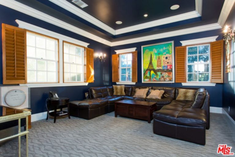 宽敞的起居空间，地毯地板上设有u形真皮沙发，周围环绕着蓝色的墙壁和天花板。
