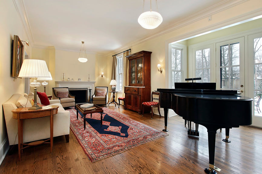 这间客厅设有优雅的座椅和一个大壁炉，以及覆盖硬木地板的时尚地毯。还有一架大钢琴，看起来很优雅。