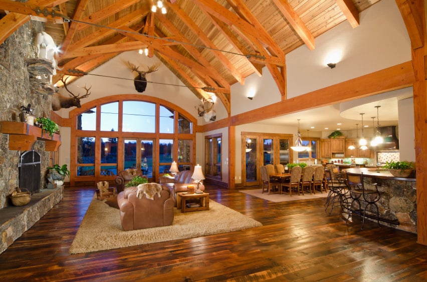 巨大的大房间设有正式的客厅，在深色硬木地板上设置了区域地毯，空间还包括一个石头壁炉和露出横梁的高拱形天花板。
