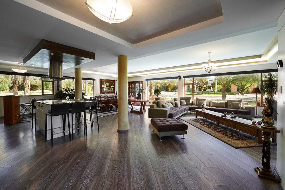 宽敞的大房间里有一张超大的l型沙发和一张特长的木制咖啡桌，咖啡桌上铺着硬木地板上的区域地毯。玻璃窗环绕着空间，吸收了充足的自然光。