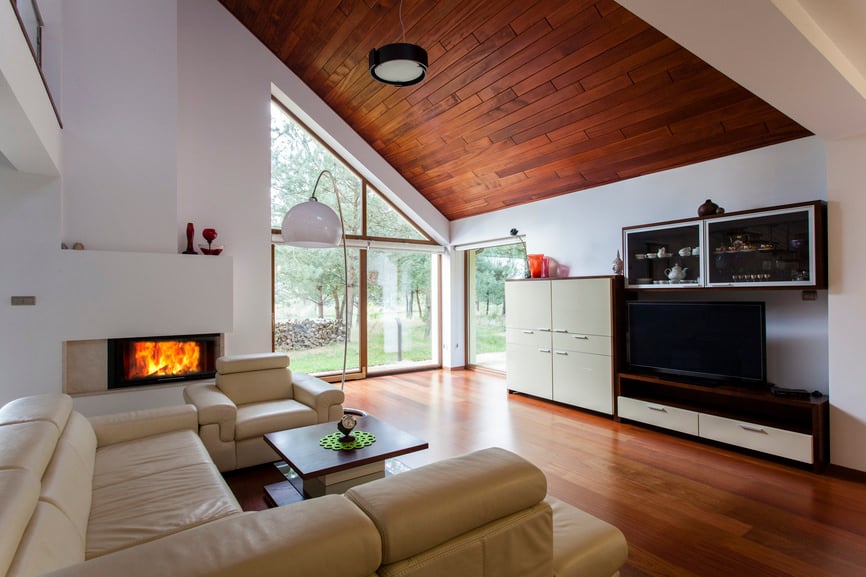 这正式的客厅里有一个壁炉和一个滑动玻璃门山墙。空间还包括一套沙发和椅子和一张咖啡桌面对电视,以及存储柜。实木地板匹配中使用的木镶板脱落的天花板。