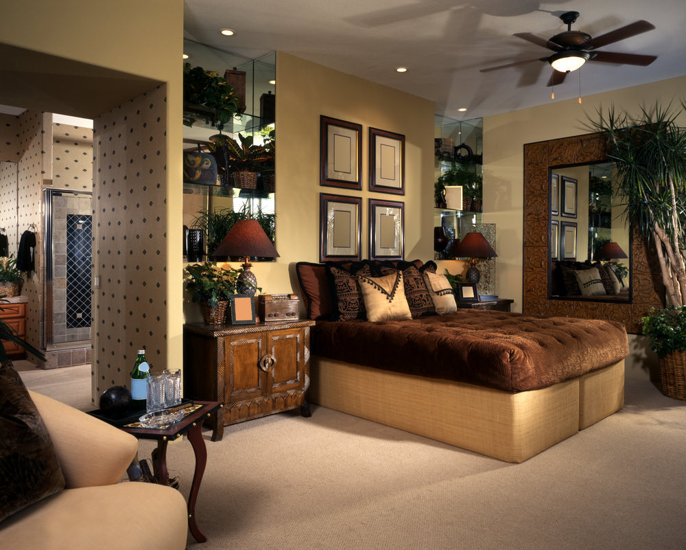 米色的主卧室设计有盆栽和画廊框架安装在棕色的床上，与它一侧的巨大镜子相辅相成。