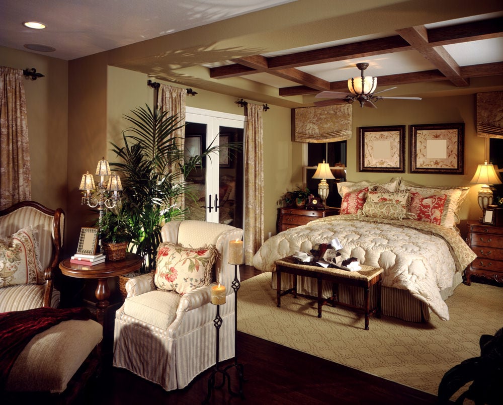 主卧室采用红色硬木地板，上面铺着与米黄色墙壁相匹配的地毯。天花板上有裸露的横梁。