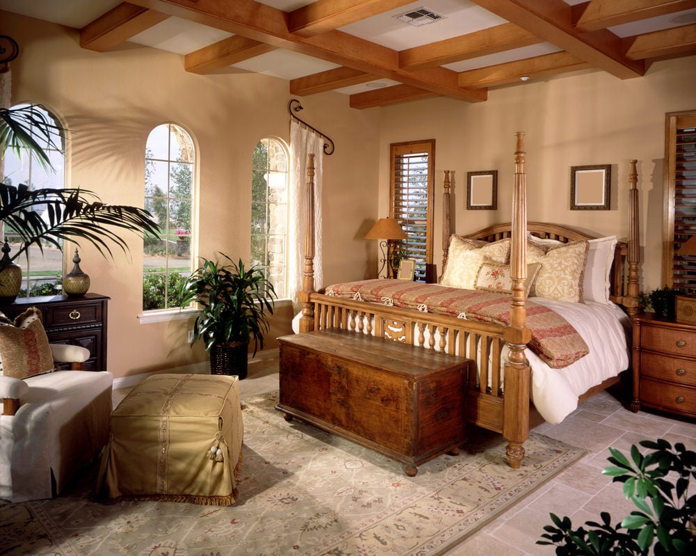 这间主卧拥有灰色瓷砖地板，上面铺着地毯。房间里有一个花哨的床架，四周是米色的墙壁。
