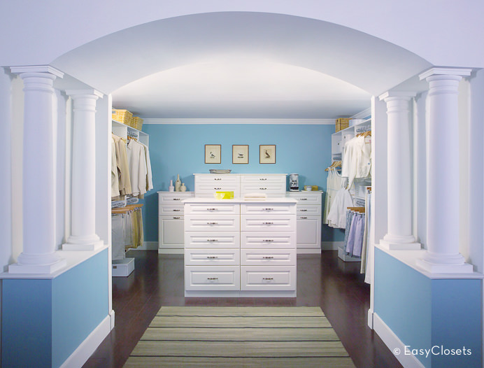 这个卧室衣柜提供了蓝色和白色的组合。蓝色的墙壁与白色的天花板和橱柜很好地融合在一起。有一个拱形走廊为房间增添了风格。