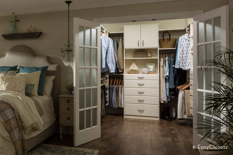 小卧室壁橱设有硬木地板和白色橱柜以及法式门。