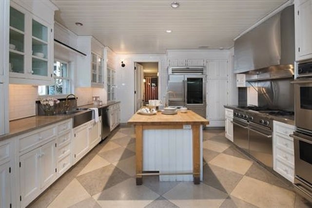 农舍u型厨房，白色橱柜，不锈钢电器，以及一个木质台面的厨房岛台位于房间中央。