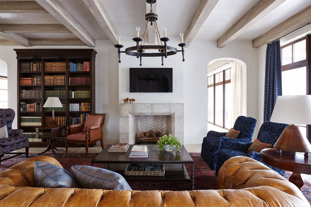 簇绒沙发面对雪佛龙壁炉和电视在这个客厅一木书架,伴随着不匹配的椅子和圆桌。