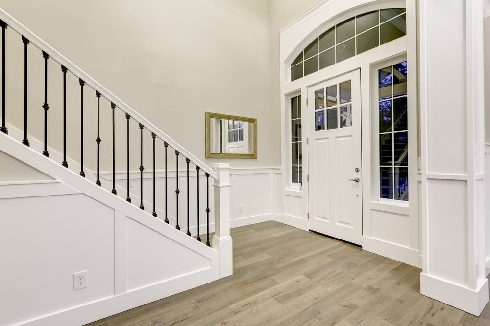 这间门厅铺着硬木地板，四周环绕着白色的墙壁、门和天花板。