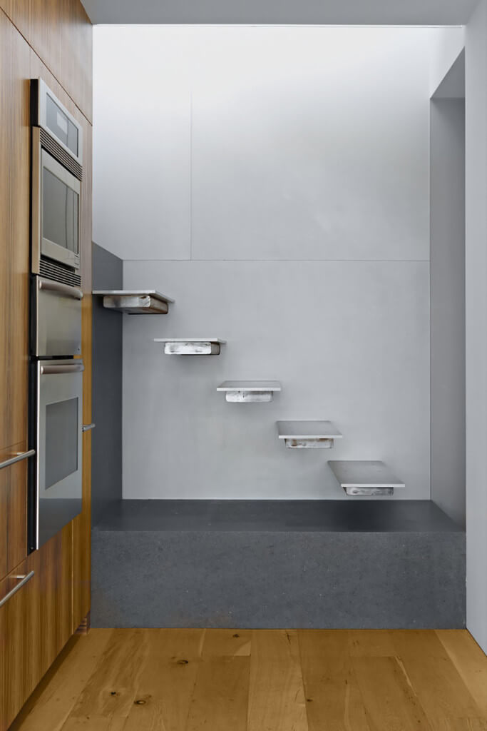 光滑的楼梯展示了深灰色的混凝土平台和固定在浅灰色墙壁上的现代金属踏板。