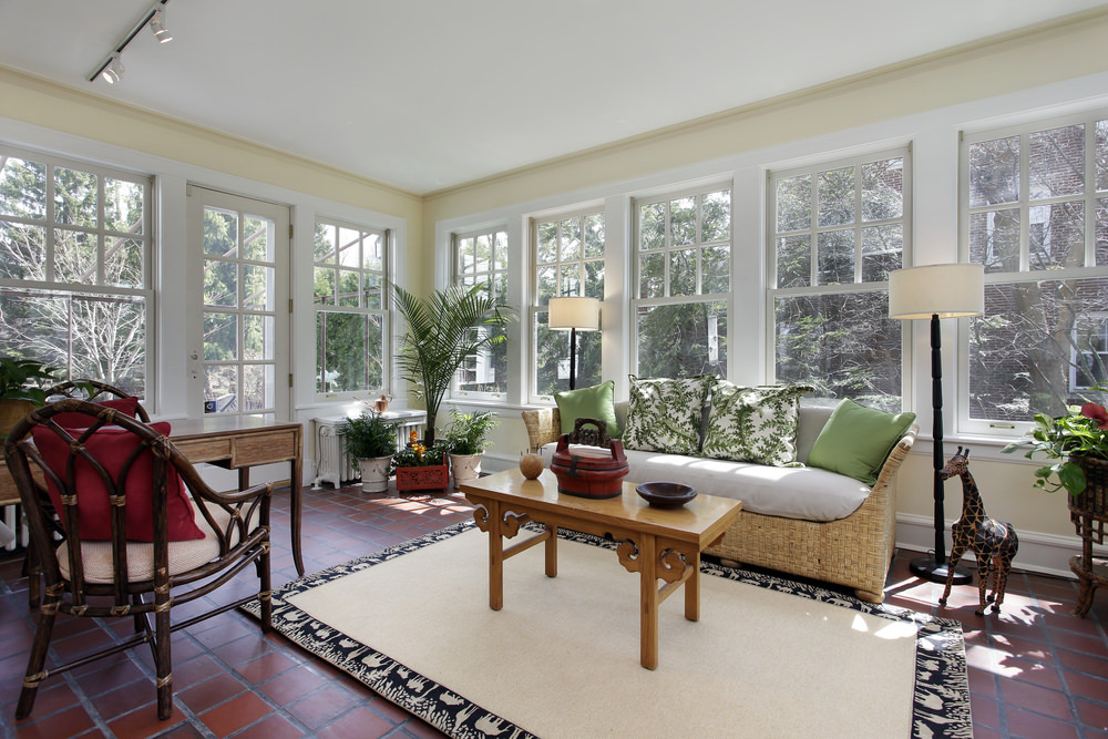 一个清新优雅的客厅，有几个玻璃窗、盆栽植物和印花抱枕，以配合气氛。