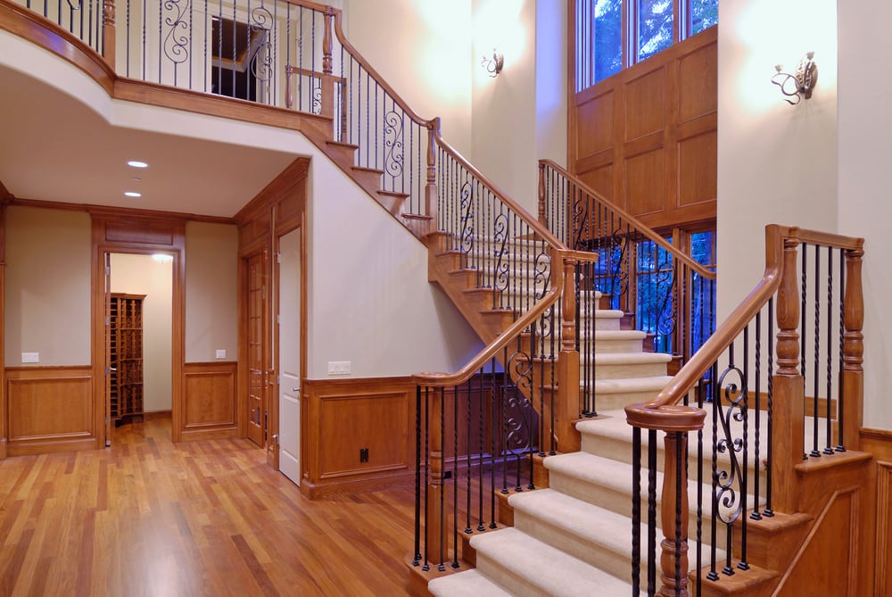 豪华的楼梯，地毯地板，棕色木扶手和黑色铁栏杆。