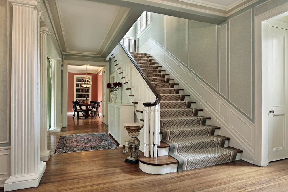 一条笔直的楼梯，地板上铺着漂亮的地毯。这所房子的墙壁看起来很吸引人。