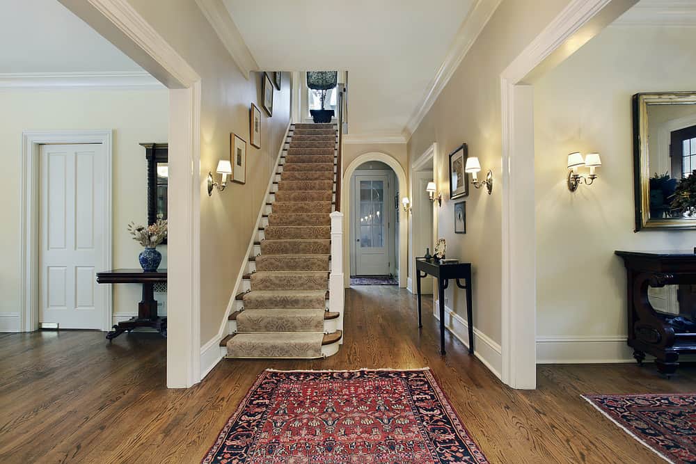 楼梯笔直，地板上有漂亮的地毯。墙壁上装饰着三个墙壁装饰品和一个壁灯。