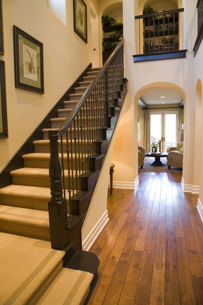 l型楼梯，配有可爱的地毯地板和铁栏杆，以及多个墙壁装饰。