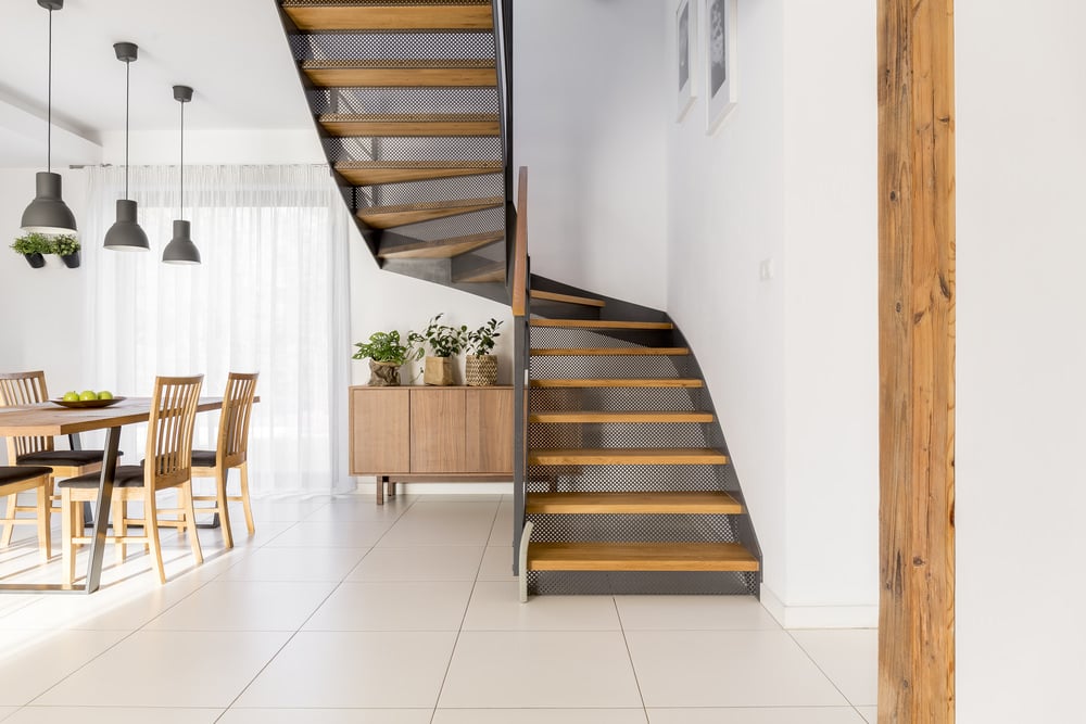 新鲜的用餐区铺设白色瓷砖地板，设有带穿孔钢立管和木踏板的楼梯。