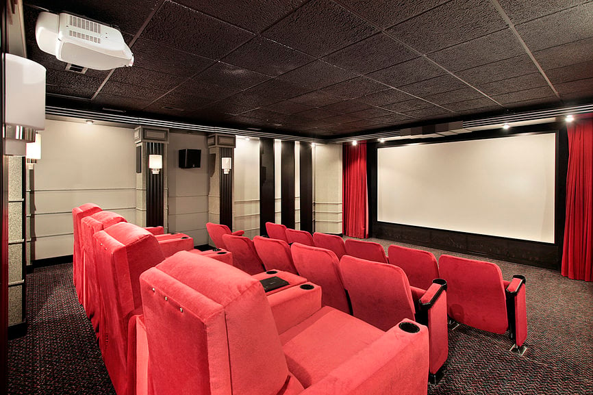 大型家庭影院，黑色天花板和红色座椅设置在时尚的地毯地板上。