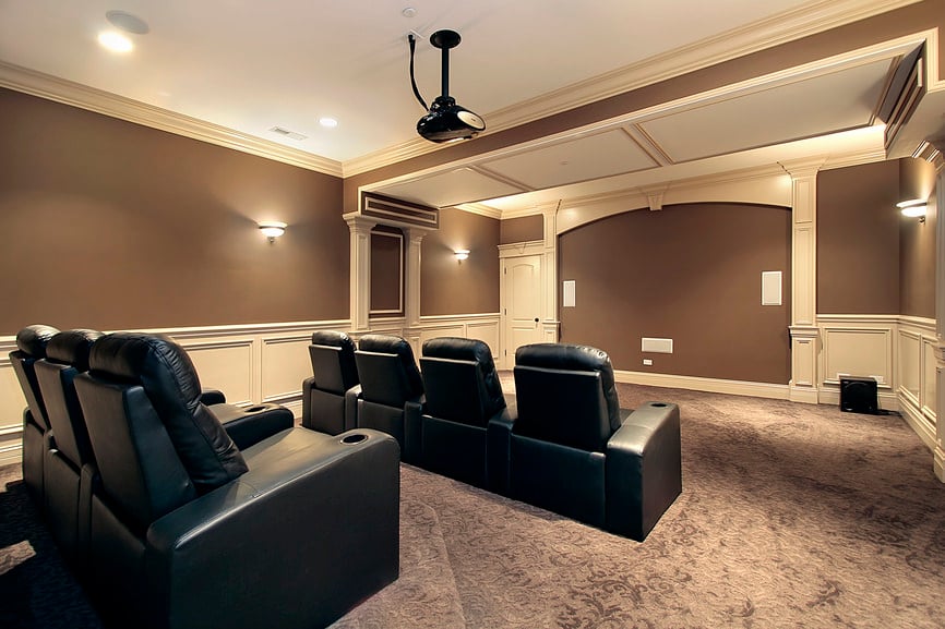大型家庭影院，棕色和白色的墙壁和天花板，以及可爱的地毯地板和优雅的黑色影院座椅。