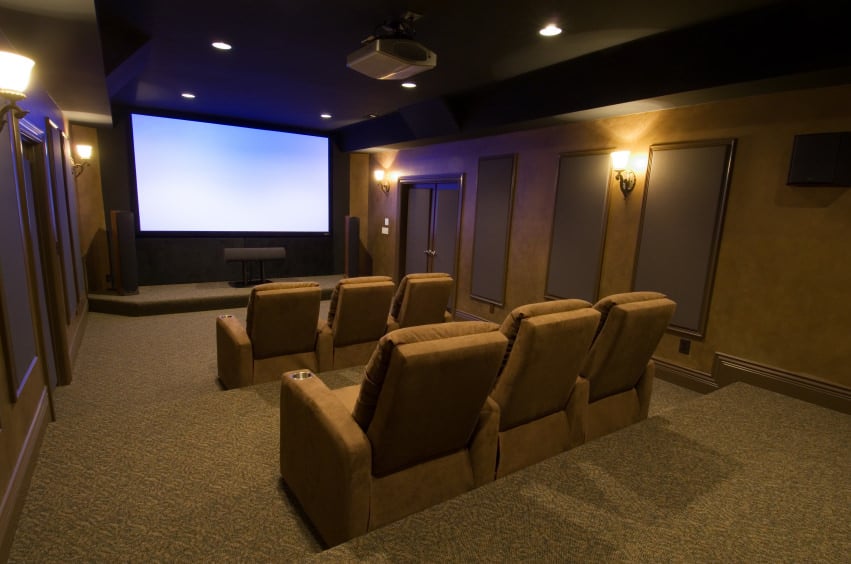 一个大型家庭影院，配有一套漂亮的影院座位，由壁灯和嵌入式天花板照明。