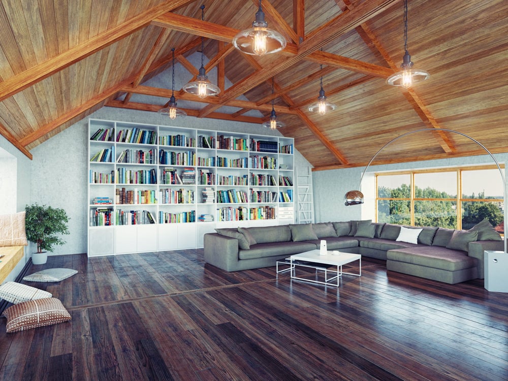 大客厅，有一个巨大的灰色沙发和硬木地板。该区域以拱形天花板和白色书架墙为特色。