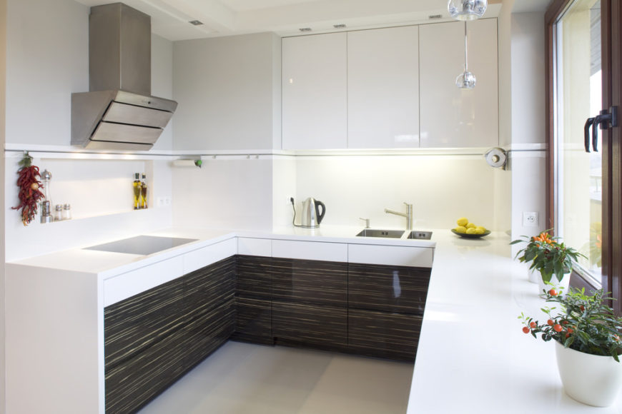 这间厨房以白色橱柜、墙壁和光滑的白色台面为特色。