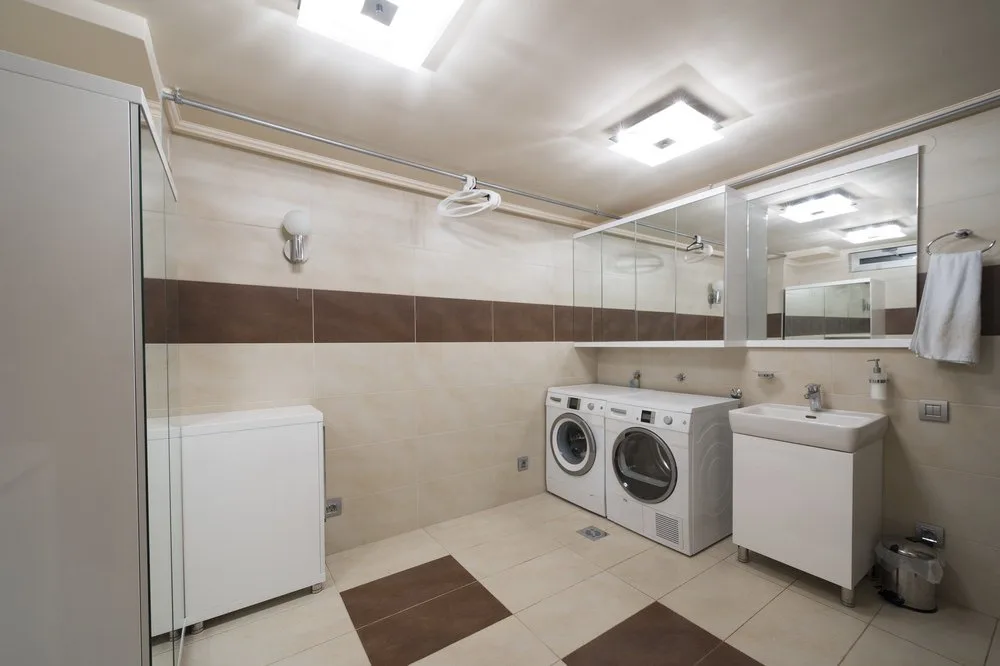使用瓷砖墙壁和地板上在洗衣房,以高效洗衣机和干衣机集实用水槽和储存柜。
