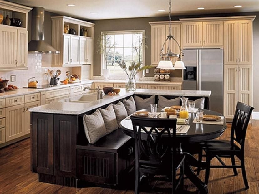 深色的木质餐厅角落和灰色的枕头连接在岛式吧台上，通过白色的床头橱柜最大化了厨房的空间。