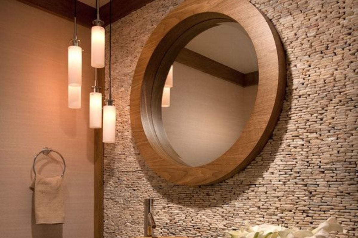 一扇木门通往这间农舍的浴室，浴室里有水槽和一面安装在拱形墙下的木制镜框镜子。