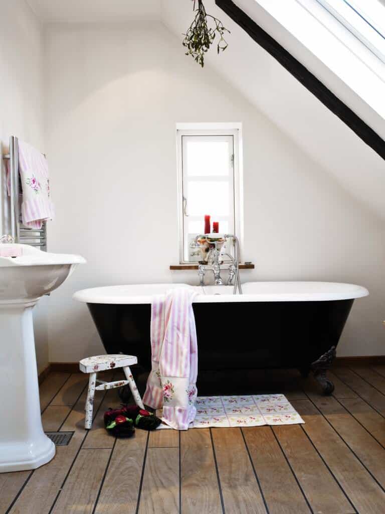 主浴室拥有一个独立的浴缸，黑色的外部设置在房间的硬木地板上。房间里还有一个洗手台。
