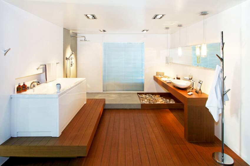 明亮的主浴室设有硬木地板和白色墙壁。它的特点是一个容器水槽和一个带有木制平台的独立式浴缸。