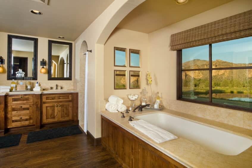 大型主浴室设有质朴的柜台和硬木地板，以及靠近窗户的落脚浴缸。